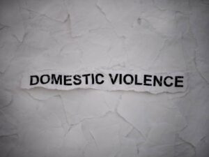 Wrinkled paper sign with cutout words reading domestic violence for a life coaching blog post about overcoming domestic violence.