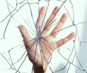 alm of a hand pressed against cracked glass, symbolizing the isolation and impact of the crimes of domestic violence.